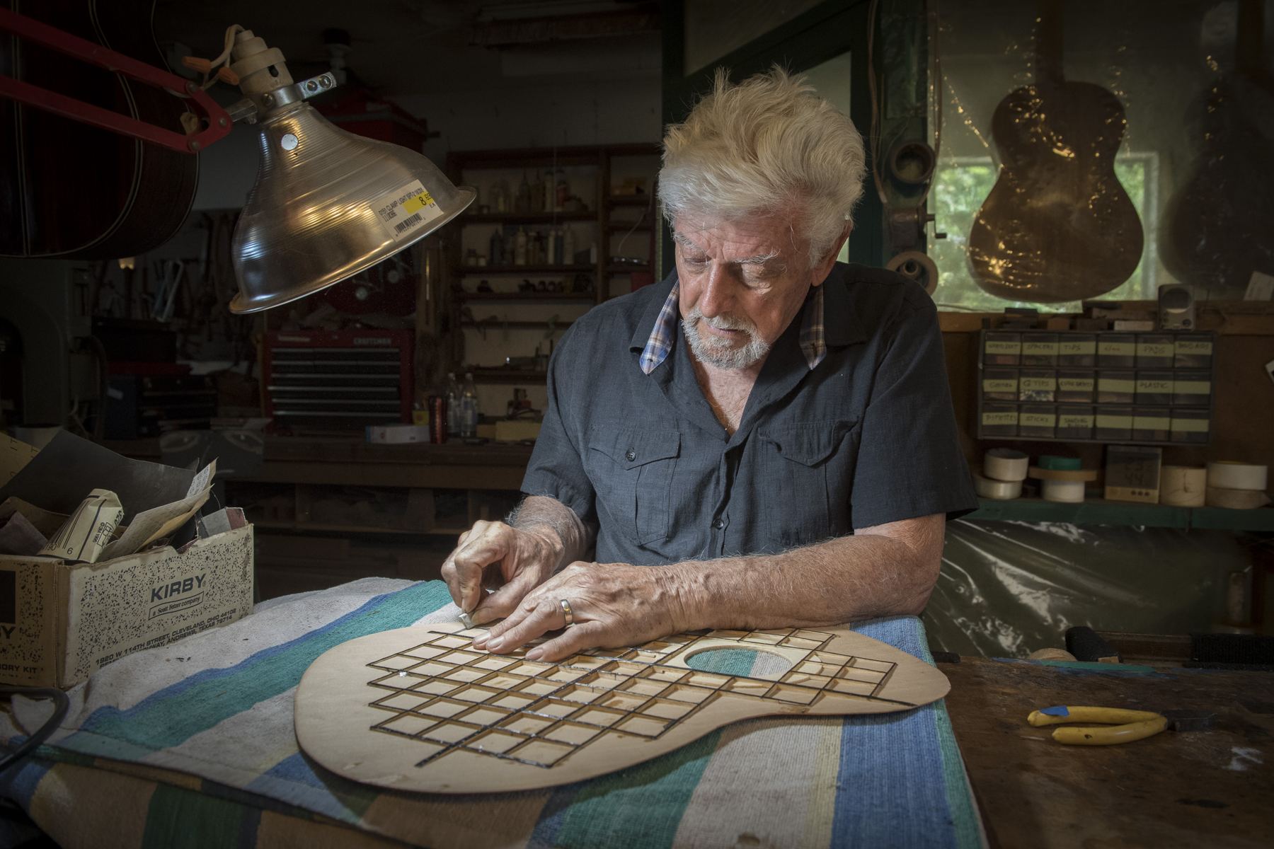 Gil Carnal at his workbench, fitting a lattice of thin struts to the underside of a guitar soundboard