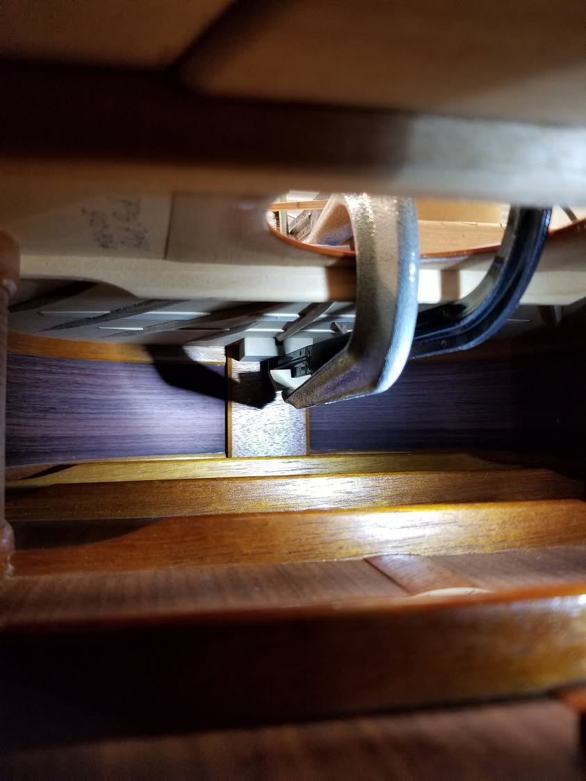 Inside the guitar, seen through the soundhole: the foot of the clamp pressing the repair against the underside of the top