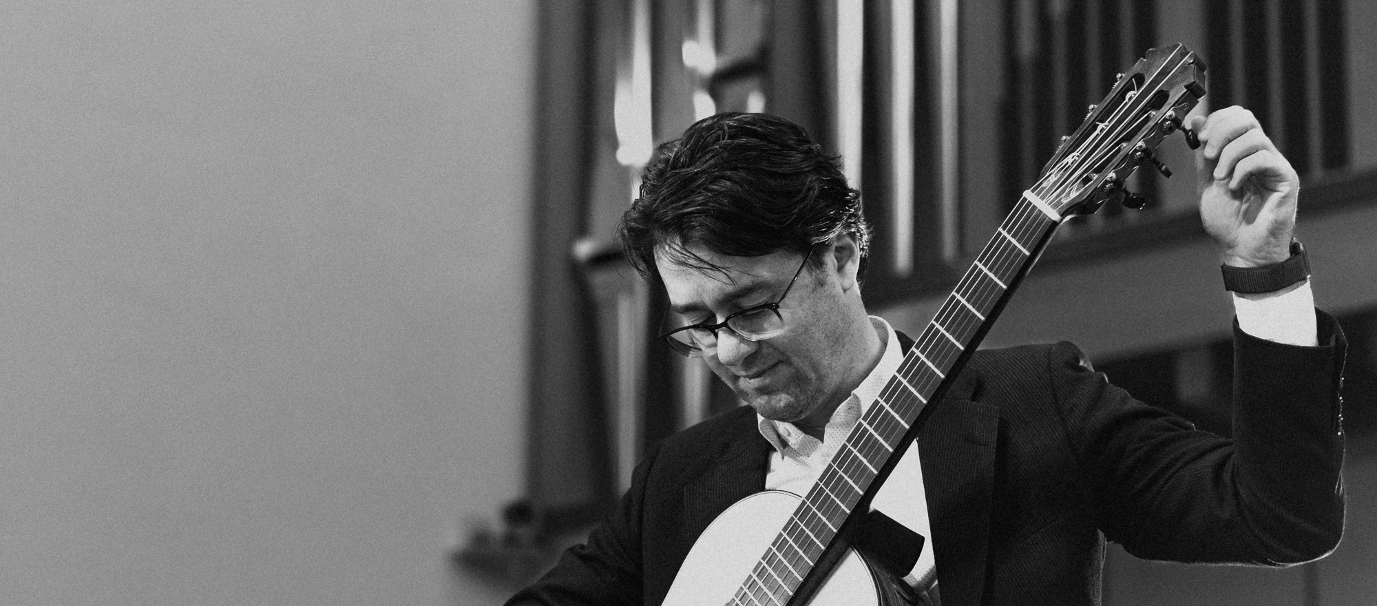 Yuri Liberzon tuning his guitar on stage, organ pipes behind