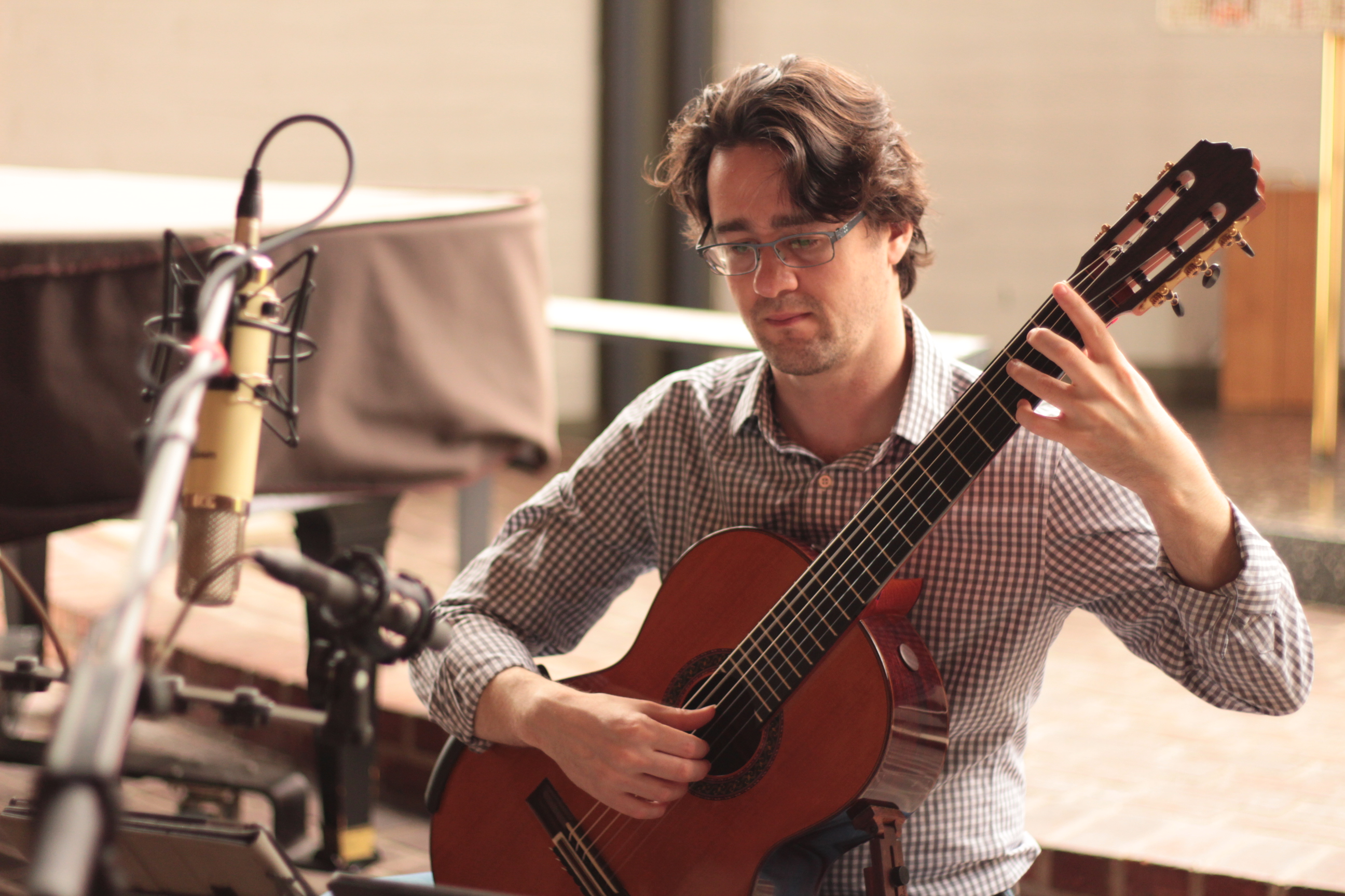 Yuri Liberzon recording Bach on guitar among microphones in the studio.