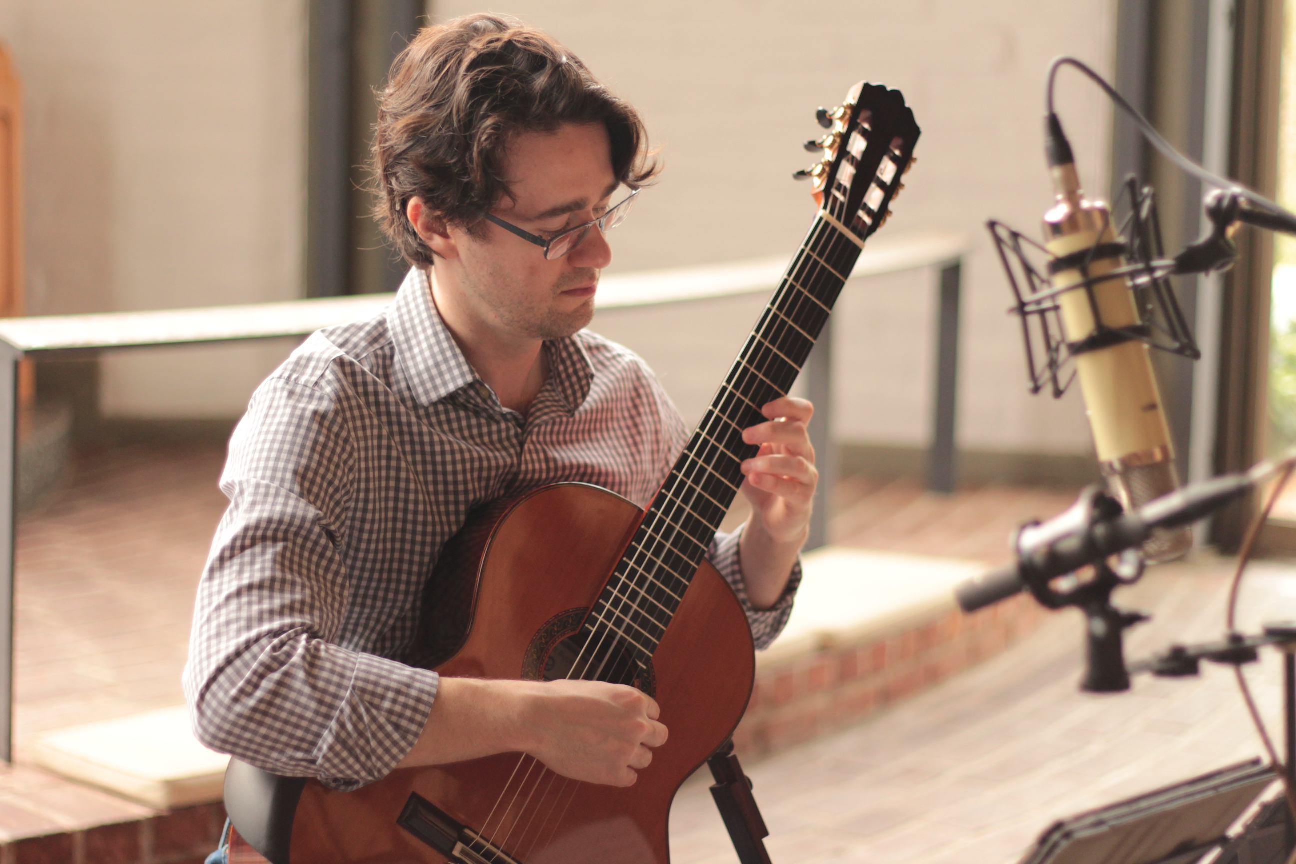 Yuri Liberzon playing guitar beside a large studio microphone during the Bach recording session.